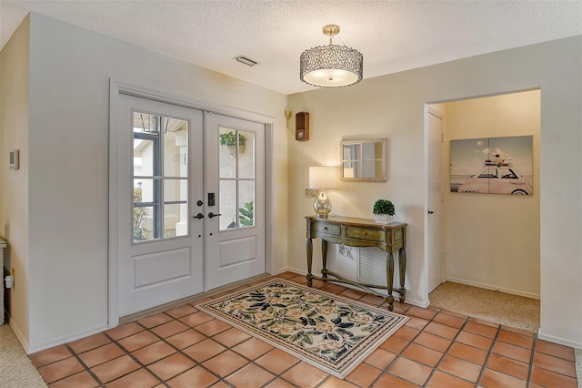 tiled foyer entrance featuring french doors and a textured ceiling