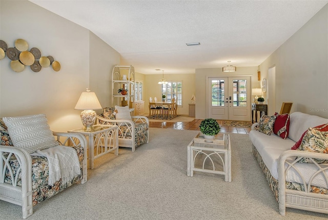 living room featuring a textured ceiling, a notable chandelier, tile patterned floors, and french doors