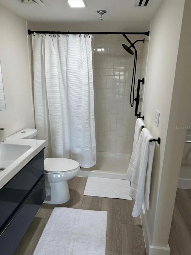 bathroom with vanity, toilet, wood-type flooring, and walk in shower