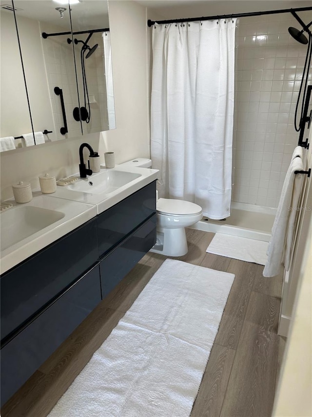 bathroom featuring hardwood / wood-style floors, walk in shower, toilet, and double sink vanity