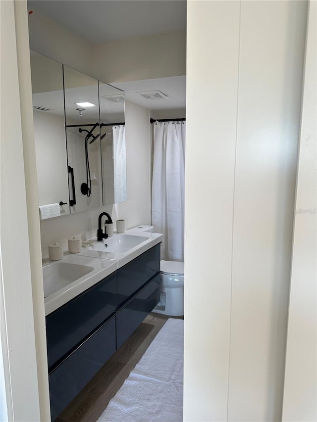 bathroom with toilet, hardwood / wood-style flooring, and dual vanity