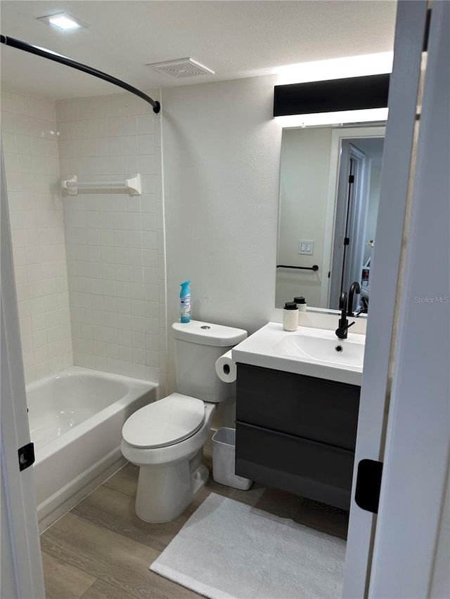 full bathroom featuring wood-type flooring, toilet, tiled shower / bath, and vanity