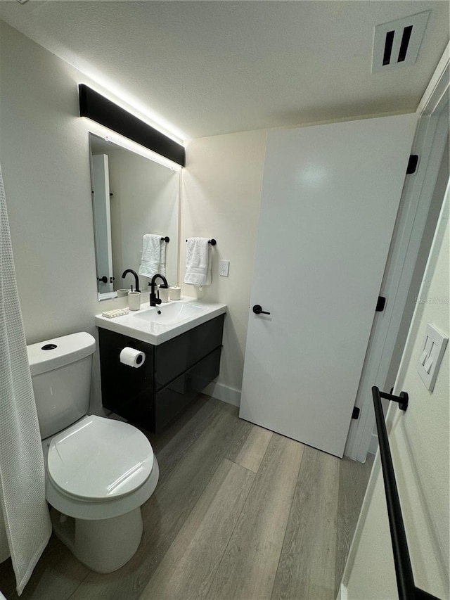 bathroom featuring vanity, toilet, and hardwood / wood-style floors