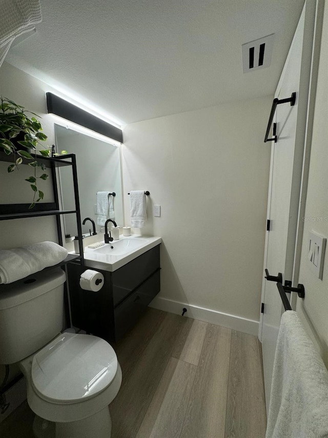 bathroom featuring hardwood / wood-style floors, toilet, a textured ceiling, and vanity