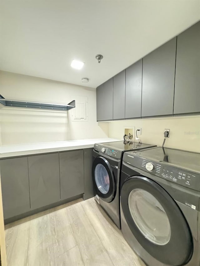 laundry area with cabinets, independent washer and dryer, and light hardwood / wood-style floors