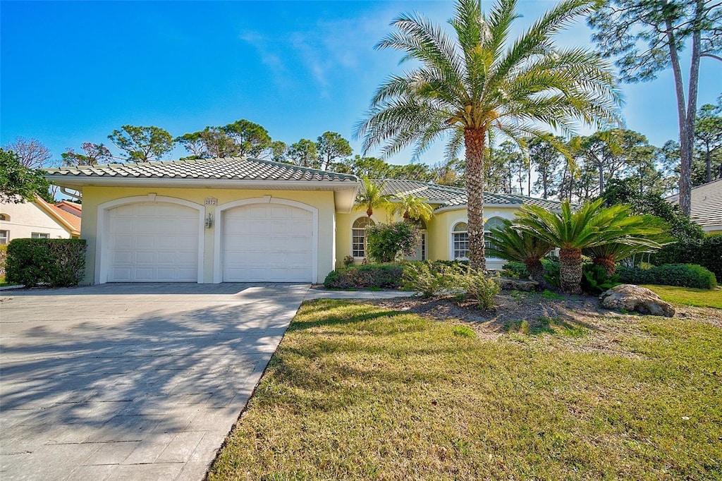 mediterranean / spanish home featuring a front yard and a garage