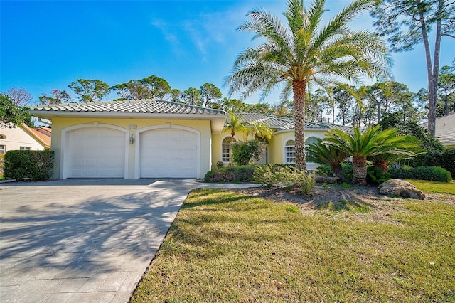 mediterranean / spanish home featuring a front yard and a garage