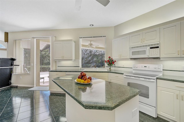 kitchen with a kitchen island, ceiling fan, white appliances, backsplash, and dark tile floors