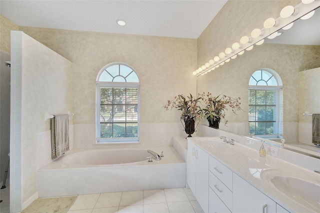 bathroom featuring tile flooring, dual bowl vanity, a bath to relax in, and a wealth of natural light