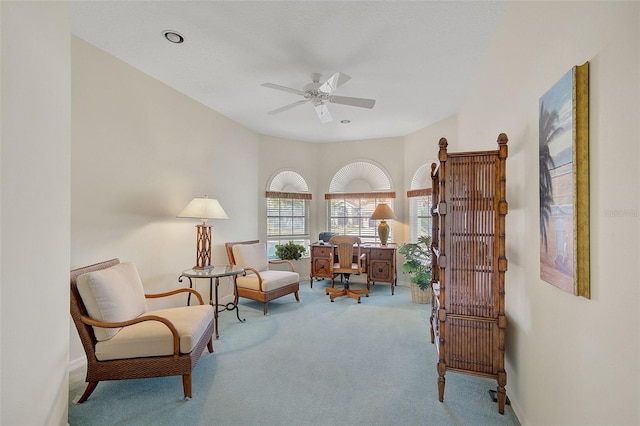 living area with light colored carpet and ceiling fan