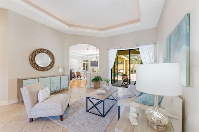 tiled living room with a chandelier and a raised ceiling