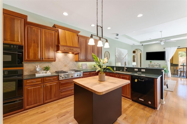 kitchen featuring light hardwood / wood-style floors, ceiling fan, black appliances, and a center island