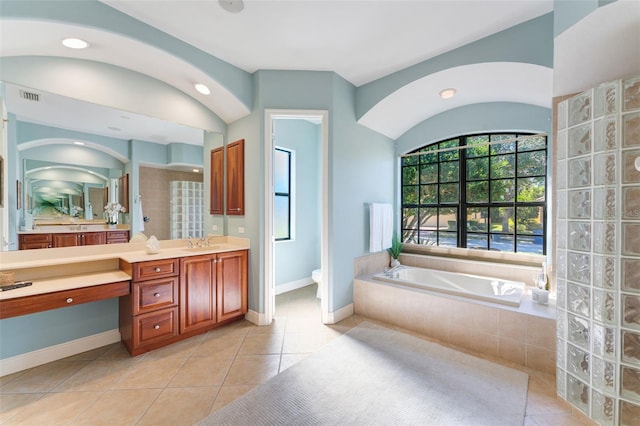 bathroom with vanity, tile floors, toilet, and tiled tub