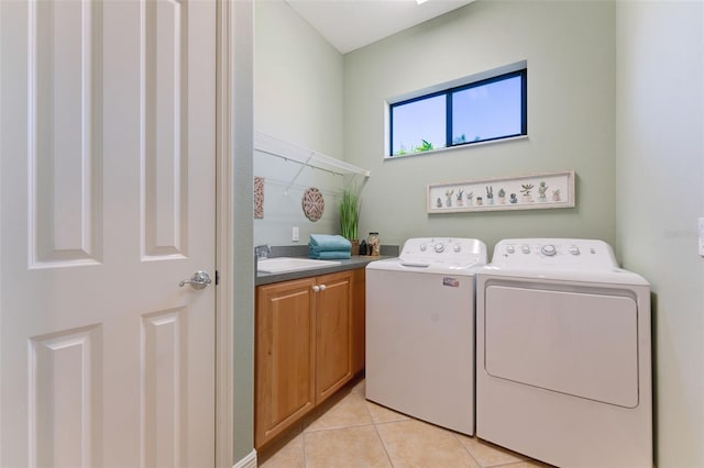 clothes washing area with cabinets, light tile floors, washing machine and clothes dryer, and sink