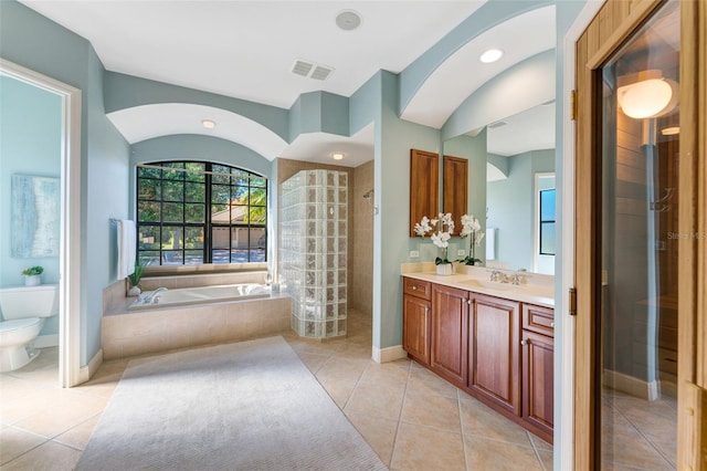 full bathroom featuring shower with separate bathtub, toilet, vanity with extensive cabinet space, and tile floors