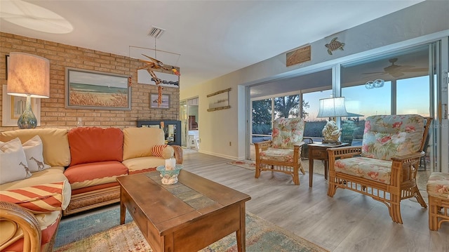 living room featuring brick wall, light hardwood / wood-style floors, and ceiling fan