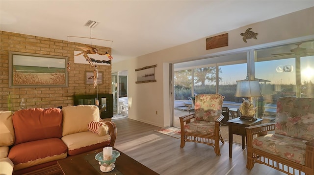 living room featuring brick wall, hardwood / wood-style flooring, and a fireplace