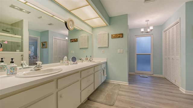 bathroom with an inviting chandelier, dual vanity, and hardwood / wood-style flooring