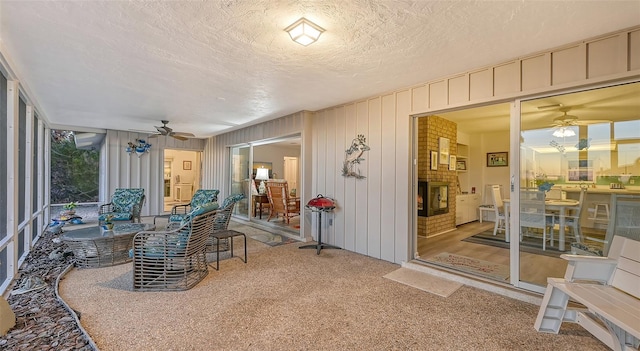 sunroom featuring ceiling fan and a fireplace