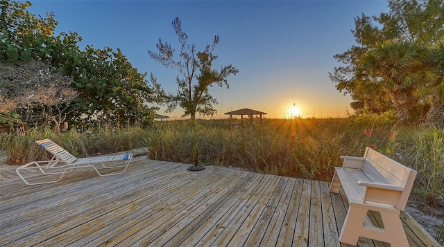 deck at dusk featuring a gazebo