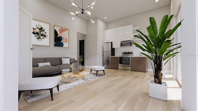 living room featuring a towering ceiling, a notable chandelier, and light hardwood / wood-style flooring