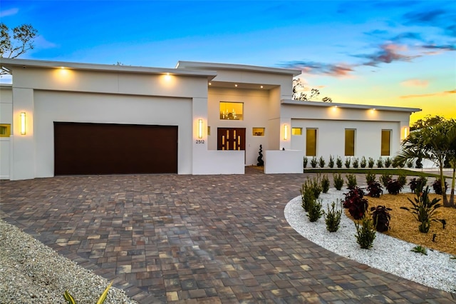 modern home with a garage, decorative driveway, and stucco siding