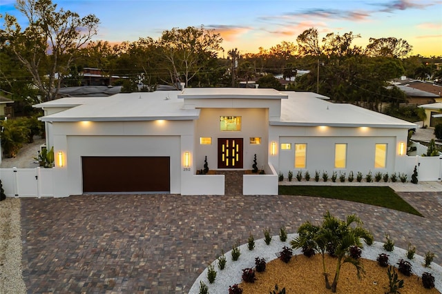 view of front of home featuring a garage, fence, decorative driveway, a gate, and stucco siding