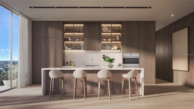 bar with oven, wooden walls, dark brown cabinets, light hardwood / wood-style floors, and a wall of windows