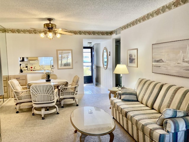 living room featuring a textured ceiling, ceiling fan, and light tile floors