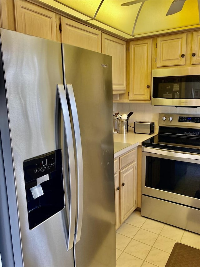 kitchen with backsplash, ceiling fan, appliances with stainless steel finishes, light tile floors, and light brown cabinetry