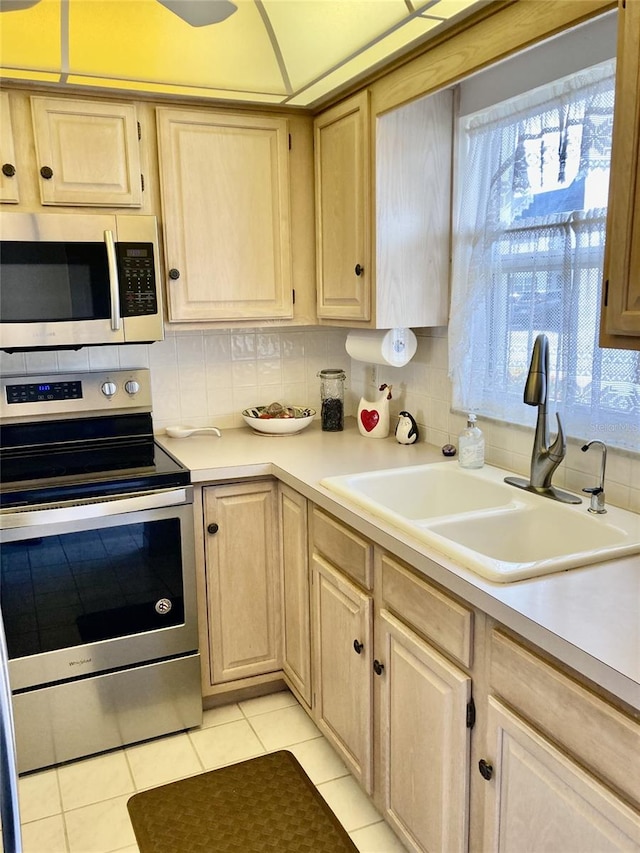 kitchen with light brown cabinetry, sink, light tile floors, appliances with stainless steel finishes, and tasteful backsplash