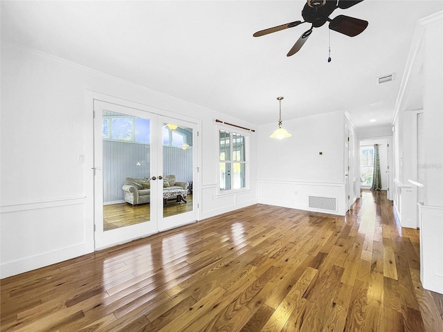 empty room featuring plenty of natural light, ornamental molding, ceiling fan, and dark wood-type flooring