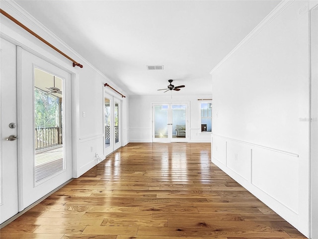 empty room with ceiling fan, light hardwood / wood-style flooring, french doors, and crown molding