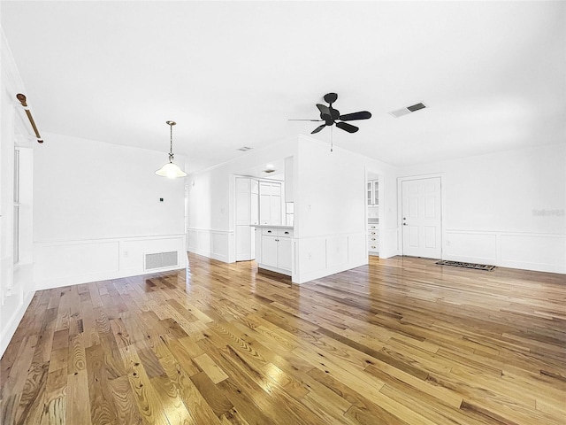 unfurnished living room with crown molding, light hardwood / wood-style floors, and ceiling fan