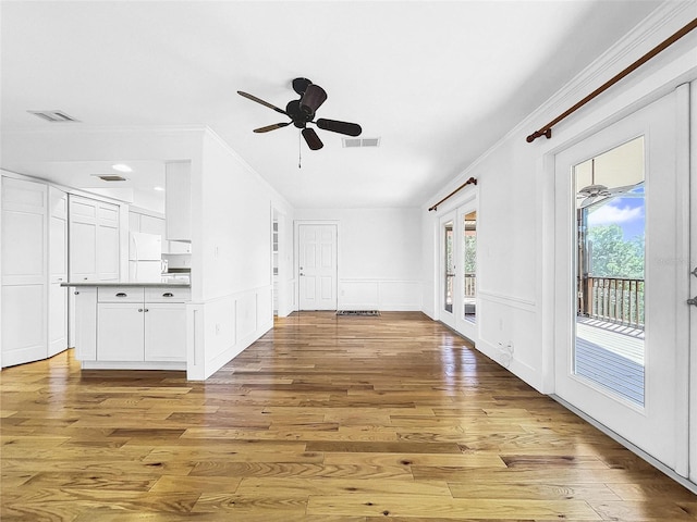 unfurnished living room featuring light hardwood / wood-style floors, ceiling fan, french doors, and crown molding