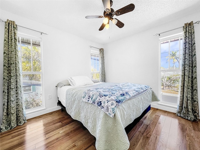 bedroom with multiple windows, ceiling fan, and dark hardwood / wood-style flooring