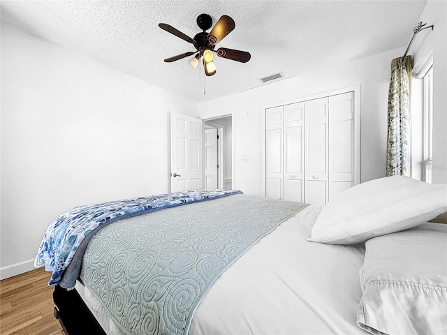 bedroom featuring a textured ceiling, a closet, ceiling fan, and light wood-type flooring