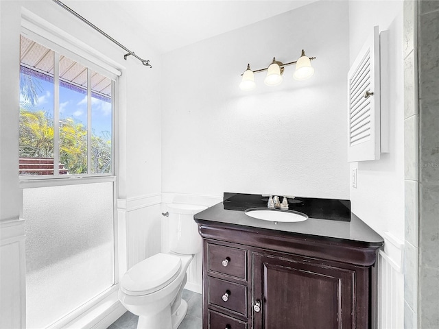 bathroom with tile floors, a shower, toilet, and vanity