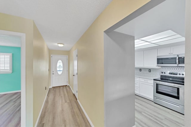 kitchen featuring backsplash, light hardwood / wood-style floors, white cabinets, and electric range oven