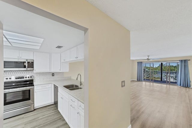 kitchen featuring ceiling fan, sink, white cabinets, appliances with stainless steel finishes, and light hardwood / wood-style floors