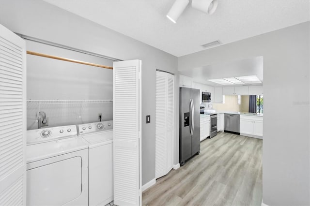 clothes washing area with hookup for an electric dryer, independent washer and dryer, and light wood-type flooring