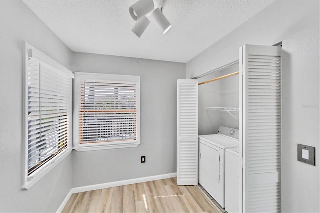 laundry room featuring washer and dryer, light hardwood / wood-style floors, and a textured ceiling