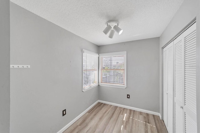 unfurnished bedroom with a textured ceiling, a closet, and light wood-type flooring