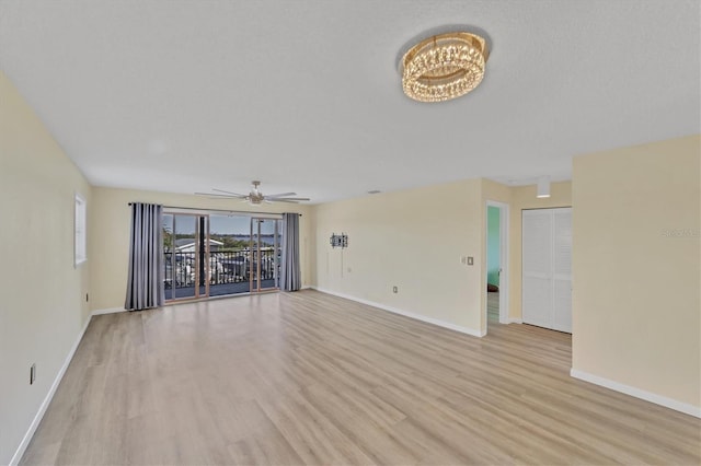 unfurnished living room featuring light wood-type flooring and ceiling fan with notable chandelier