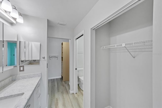 bathroom with toilet, vanity, and hardwood / wood-style floors