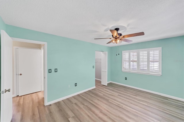 unfurnished bedroom with a closet, a textured ceiling, ceiling fan, and light wood-type flooring