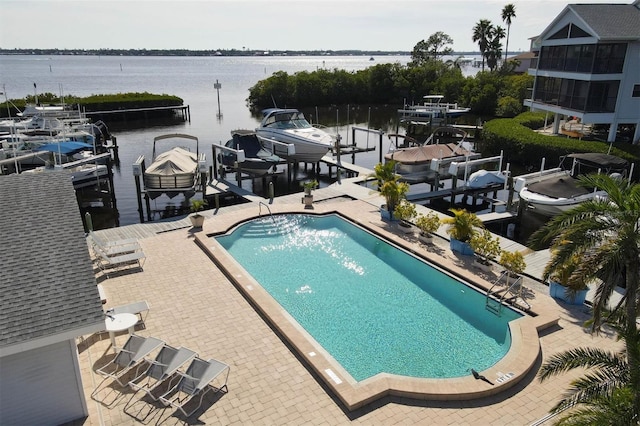 view of swimming pool featuring a dock, a water view, and a patio area