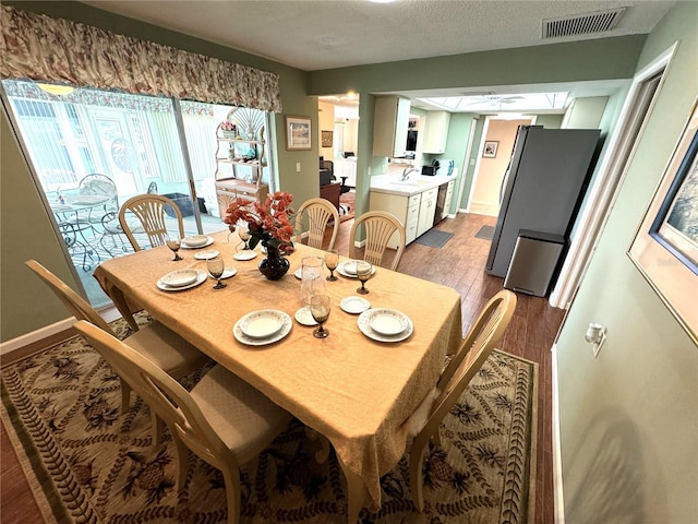 dining space featuring sink, a textured ceiling, and hardwood / wood-style flooring