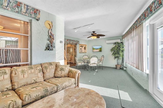 living room with carpet flooring, ceiling fan, rail lighting, an AC wall unit, and a textured ceiling