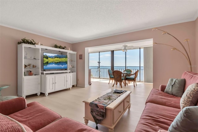 living room with ceiling fan, a textured ceiling, a water view, and light wood-type flooring